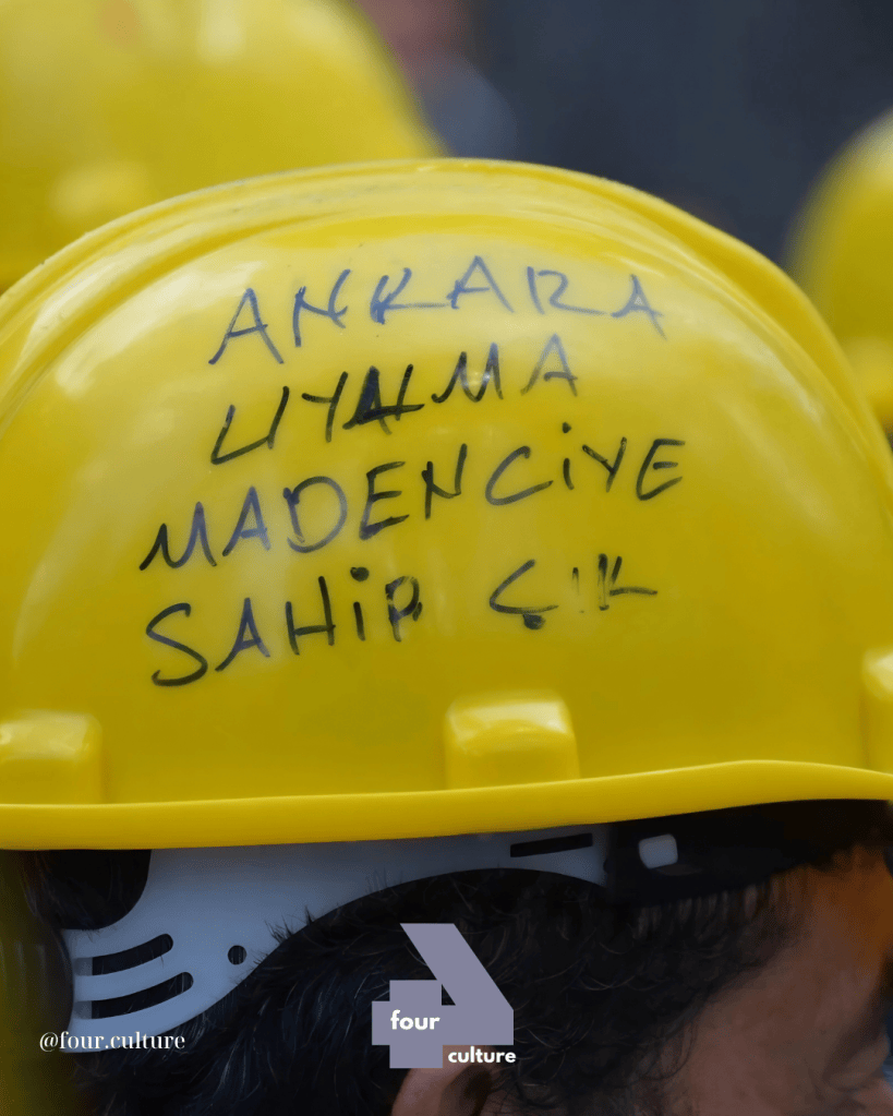 Sarı bir kaskın üzerinde siyah bir kalemle yazılmış 'ANKARA UYLAMA MADENCİYE SAHİP ÇIK' yazısı.
